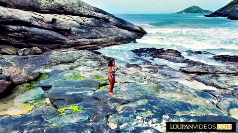 Sexy brunette in bikini posing on Brazilian beach rocks