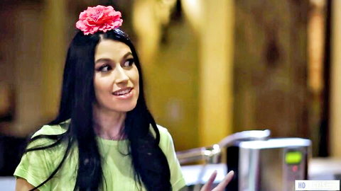 Alex Coal in green top with pink flower, smiling in sapphic UFO scene