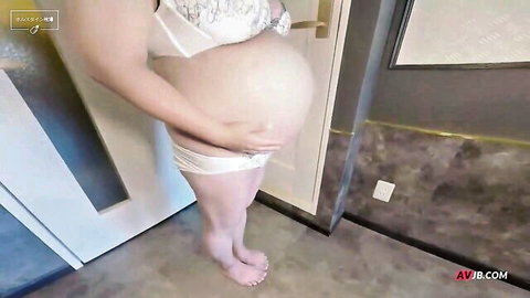 Pregnant Asian woman in white lingerie posing with hand on big belly
