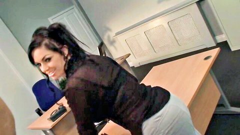 Busty brunette secretary in sheer top bending over desk, seducing boss in office