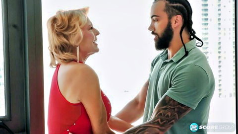 Desiree Eden, 76yo blonde MILF in red dress chats intimately with young dreadlocked stud