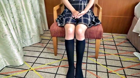 Japanese schoolgirl Misa in pleated skirt and knee socks sitting with legs apart, seductive pose