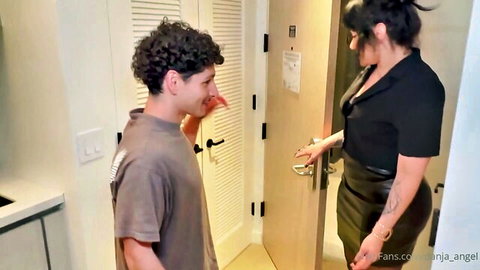 Latina in tight black leather skirt and blouse seduces curly-haired young guy puckering lips at hotel door