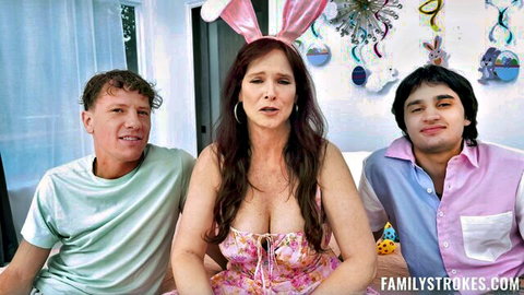 Busty brunette MILF stepmom in pink bunny dress flashing deep cleavage with two stepsons on Easter
