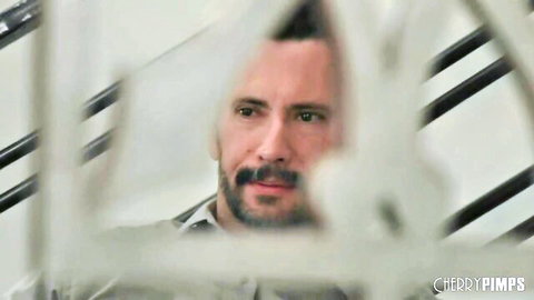 Bearded man with intense gaze peering through white stair railings in close-up view