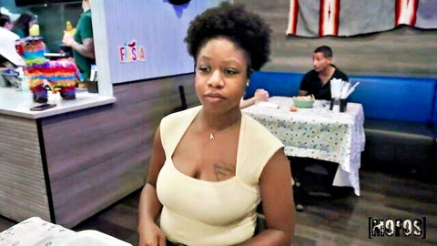 Ebony woman in low-cut top teases cleavage in public restaurant