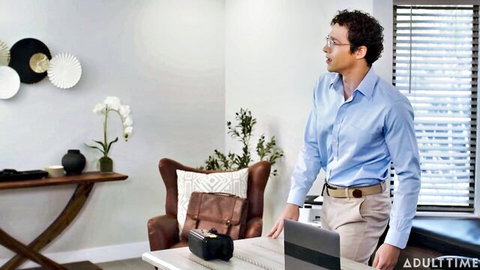 Handsome curly-haired man in blue shirt and khakis smirking in office