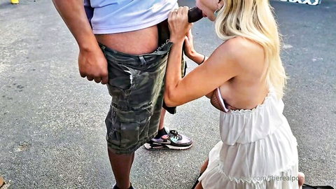 Blonde in white dress kneels for outdoor blowjob to man