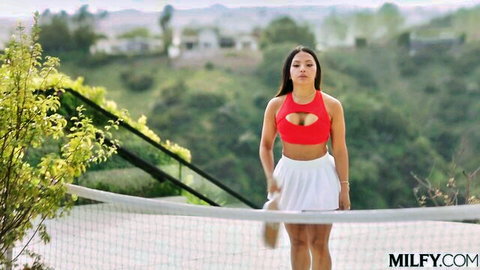 Brunette MILF teasing in red cutout bra showing cleavage and white tennis skirt on court