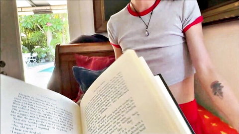Alex Adams in seductive gray crop top and red shorts, reading book teasingly