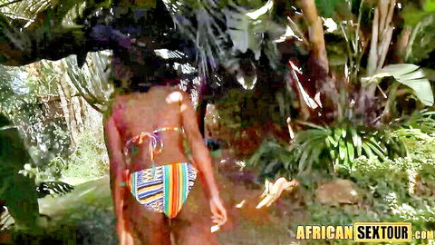 Sexy African woman in striped bikini walking in jungle backyard