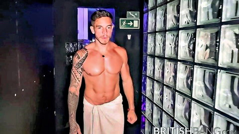 Muscular tattooed hunk in white towel teasing in locker room with ripped abs