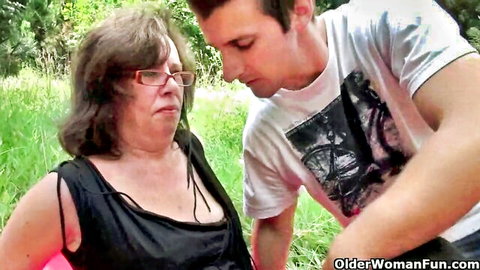 Granny grimacing during outdoor intimacy with young man