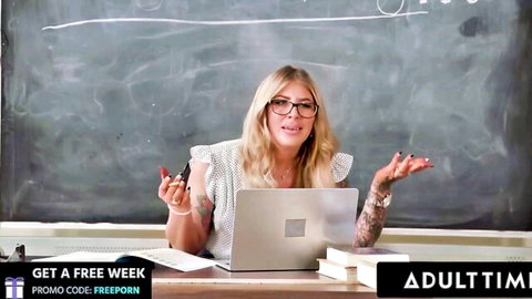 Blonde MILF teacher in glasses gesturing at desk in classroom for Adult Time free porn week