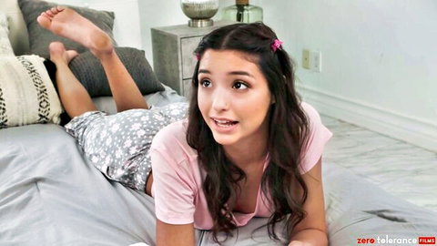 Innocent brunette in pink top and shorts lying surprised on bed with Seth Gamble