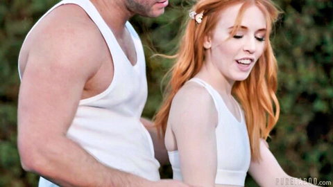 Petite redhead in white top embraced by muscular man outdoors, teasing penetration