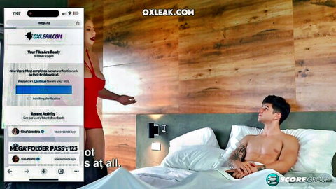 Seductive MILF in tight red dress teases topless tattooed hunk lying on bed