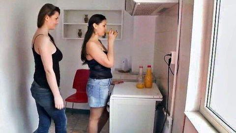 Two brunette women in tank tops teasing in kitchen, Kiss 9 scene
