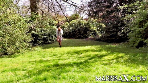 Mariska X in sexy white dress walking in lush outdoor garden
