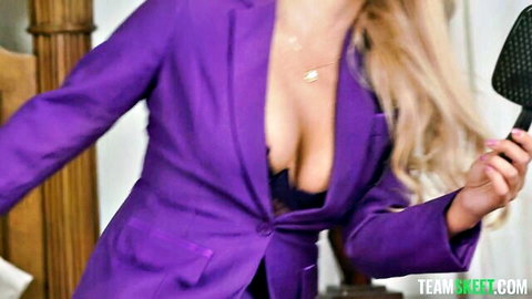 Blonde MILF in open purple suit jacket revealing black bra cleavage, holding paddle