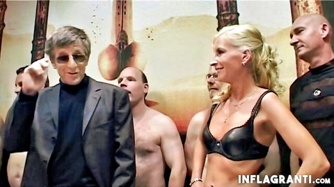 Skinny blonde in black lingerie with group of men in swinger scene