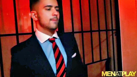 Handsome suited Latino man smiling in red-lit sex club