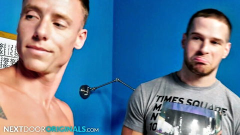 Two muscular white men, one shirtless, one in Times Square tee, teasing pose
