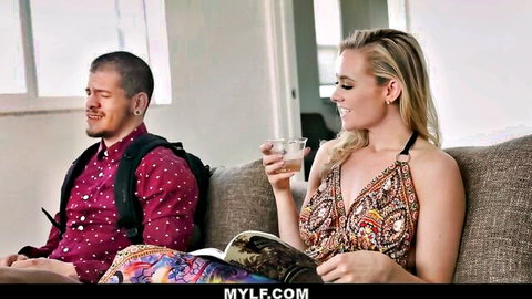 Addie Andrews as commanding stepmom in sexy dress, smiling with stepson on couch