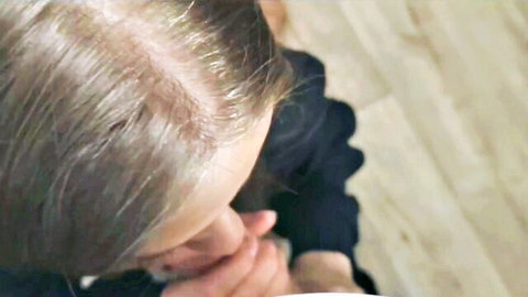 Blonde woman kneeling in dark top, close-up face in amateur blowjob scene