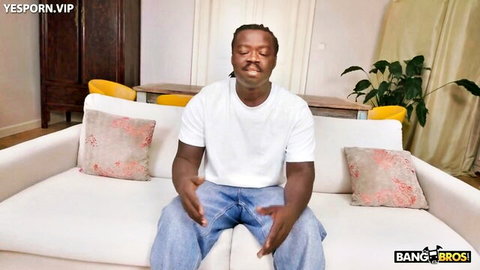 Black man in white tee and jeans sits relaxed, Miami anal preview