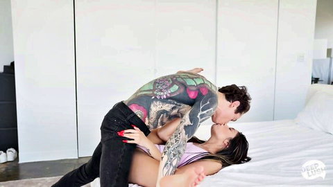 Tattooed hunk passionately fucks petite brunette missionary style kissing deeply on bed