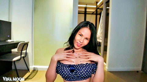 Petite Vietnamese babe in polka-dot bikini top smiling and cupping her small perky tits teasingly