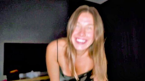 Busty blonde smiling excitedly with deep cleavage in low-cut black top