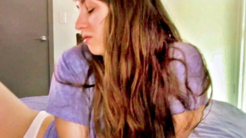 Petite brunette in purple tee and white panties on bed, teasing pose