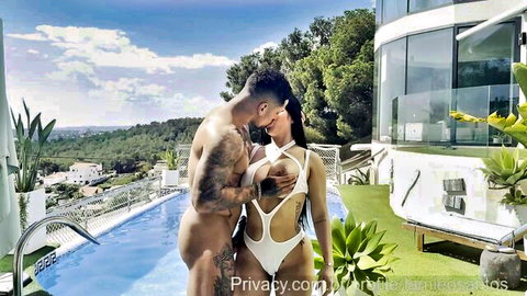 Sara Retali in skimpy bikini embraced by muscular lover poolside