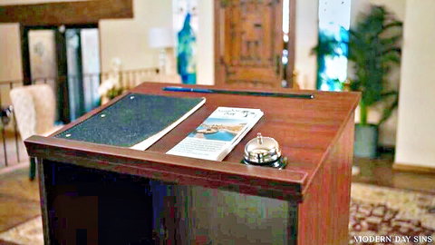 Modern Day Sins hotel reception desk with brochure and bell on wooden podium