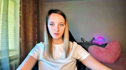 Blonde amateur webcam girl in white t-shirt posing with arms outstretched seductively