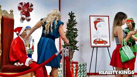 Alura TNT Jenson as sexy blonde elf in blue dress teasing Santa with brunette elf