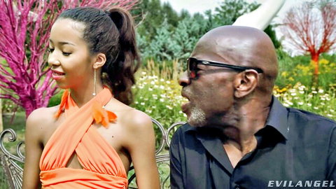 Petite ebony teen in orange halter dress with mature black stud outdoors