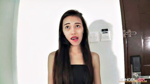 Surprised skinny Asian babe in black tube top, long hair, intense gaze