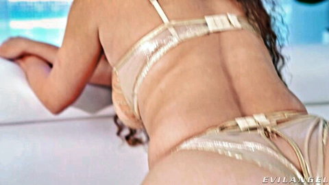Brunette in sheer gold lingerie teasing bubble butt on poolside bed