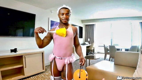 Black muscular man in sexy pink maid costume with feather duster for Halloween