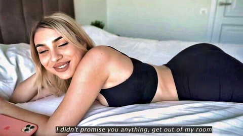 Blonde babe lying on bed in tight black bra and shorts teasing her juicy ass cheeks
