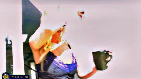Blonde MILF with big tits in low-cut purple top teasing with coffee mug