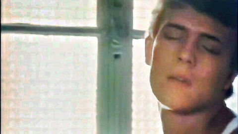 Sensual young blond man in tank top, eyes closed in erotic pose