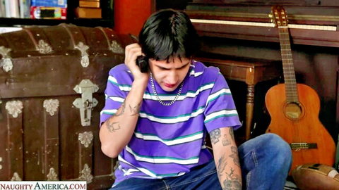 Tattooed Latino guy in striped shirt talking on retro phone