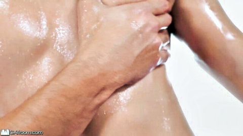 Muscular man applies oil to woman's shiny breasts in steamy intimate touch