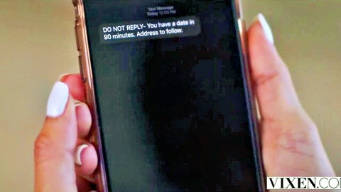 Manicured hands holding smartphone displaying 'DO NOT REPLY you have a date in 90 minutes' Vixen message
