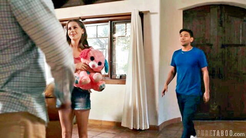 Brunette teen in shorts holds pink teddy bear with stepdad and stepbrother in taboo living room scene