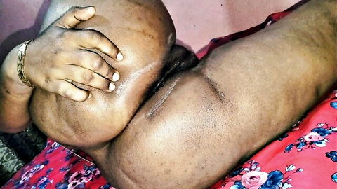 Ebony woman's massive dark ass cheeks spread wide by bracelet hand exposing tight anus on red bed